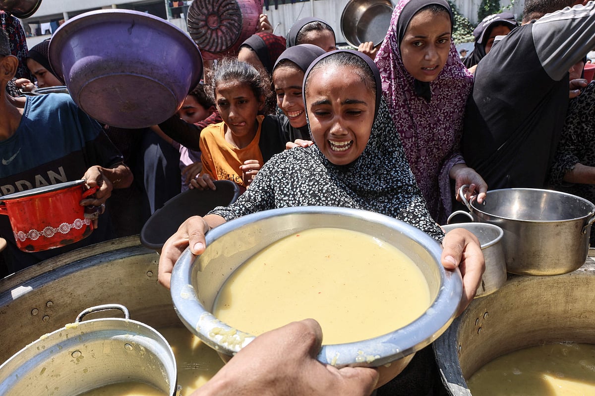 A displaced Palestinian girl reacts as she receives lentil soup at a food distribution point in Gaza City in the northern Gaza Strip on 25 July, 2025. Aid groups warned of surging numbers of malnourished children in war-ravaged Gaza as a trio of European powers prepared to hold an "emergency call" on 25 July on the deepening humanitarian crisis.