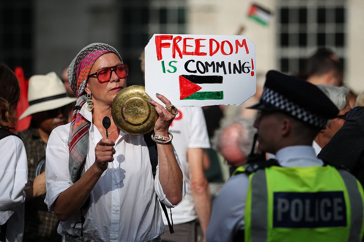 A protester holds a placard reading "Freedom is coming" and picturing the Palestinian flag during a demonstration outside Downing Street gates, in central London, on July 25, 2025, called by the Palestine Solidarity Campaign group to protest against the ongoing food shortages in the Gaza Strip.