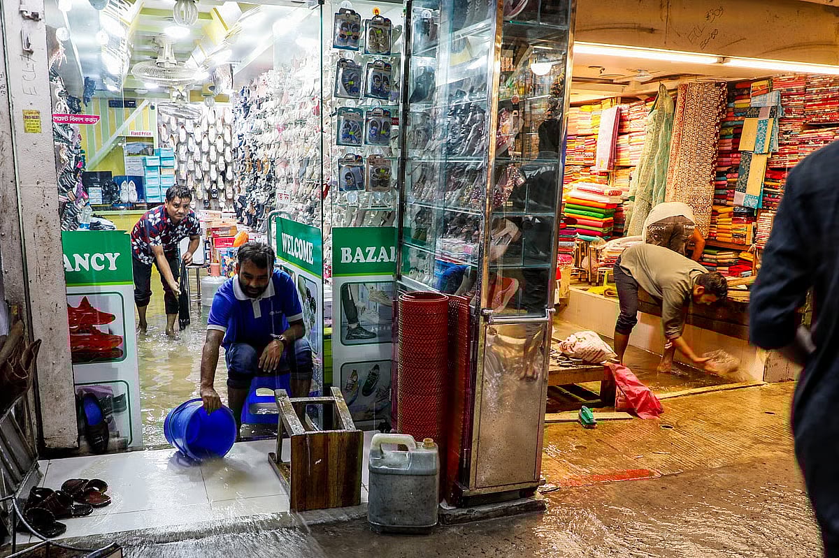 People are busy in removing water from shops at Reajuddin Bazar in Chattogram on 28 July 2025