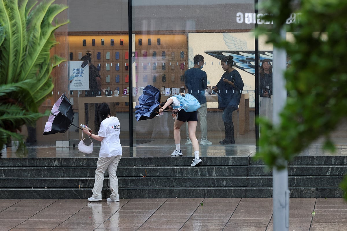 People struggle to walk during heavy rain and high winds, after Tropical Storm Co-May made landfall in a nearby city, in Shanghai, China on 30 July 2025