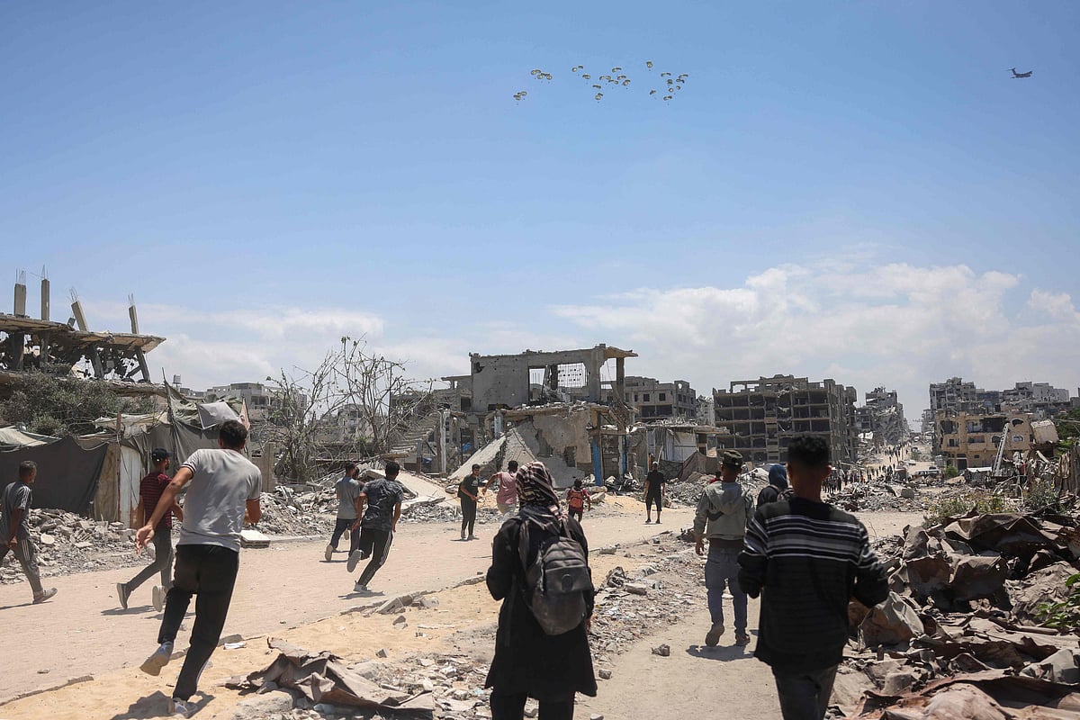 Palestinians in Jabalia in the northern Gaza Strip rush towards a plane conducting an airdrop of aid above the Israel-besieged Palestinian territory on 1 August, 2025.