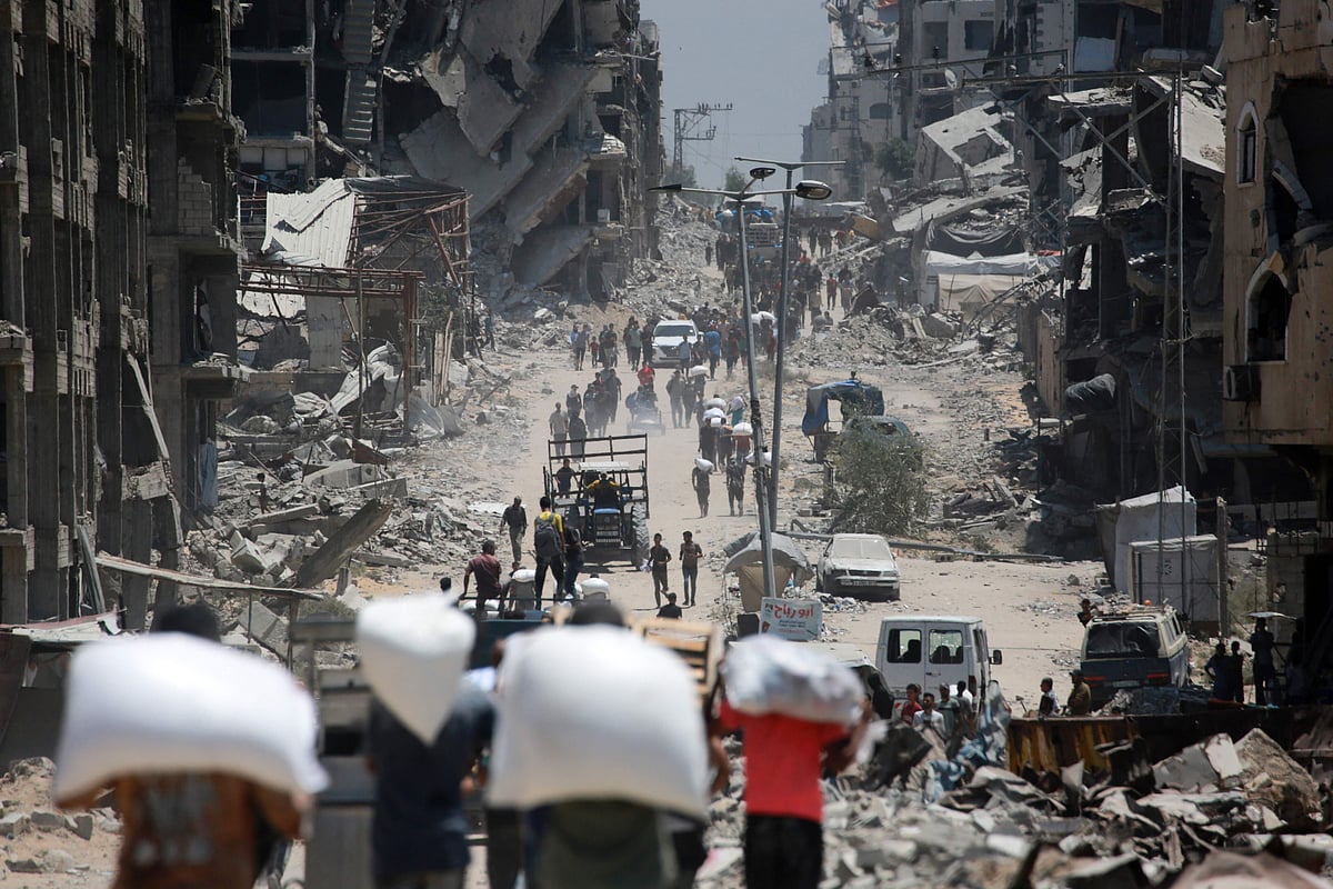 Palestinians carry bags of flour that they obtained from aid trucks which entered Gaza through the Zikim crossing point, in Jabalia in the northern Gaza Strip on 1 August, 2025. The UN human rights office said on 1 August that 1,373 Palestinians have been killed while waiting for aid in the shortage-stricken Gaza Strip since late May, most of them by the Israeli military.
