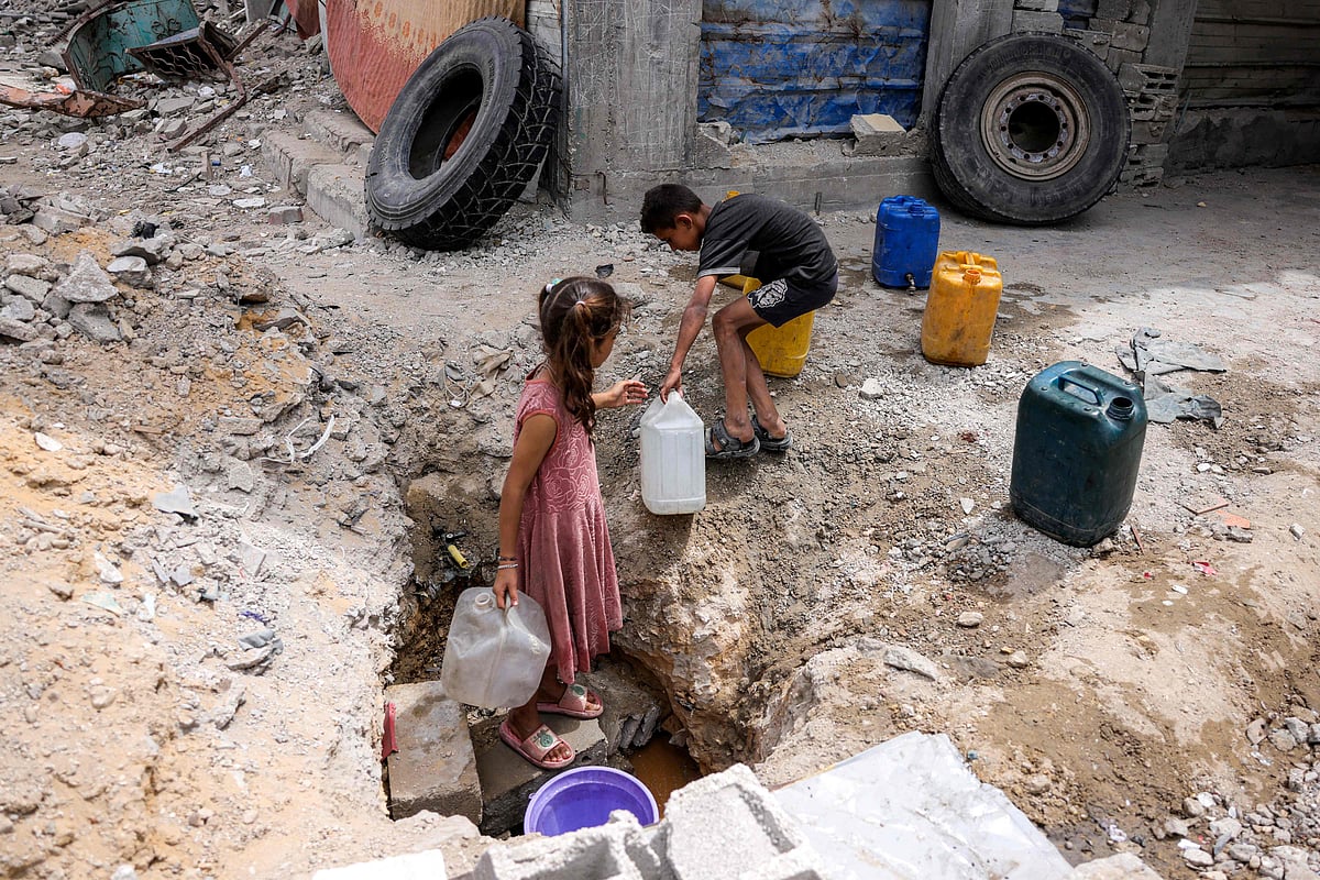 A girl fills up containers with water from the remaining water still left in underground pipes, in Beit Lahia in the northern Gaza Strip on April 24, 2025