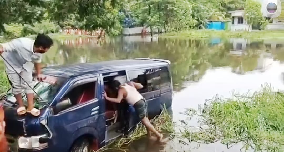Local people helping fire service men in the rescue work as a microbus plunged in a roadside canal in Noakhali on 6 August 2025