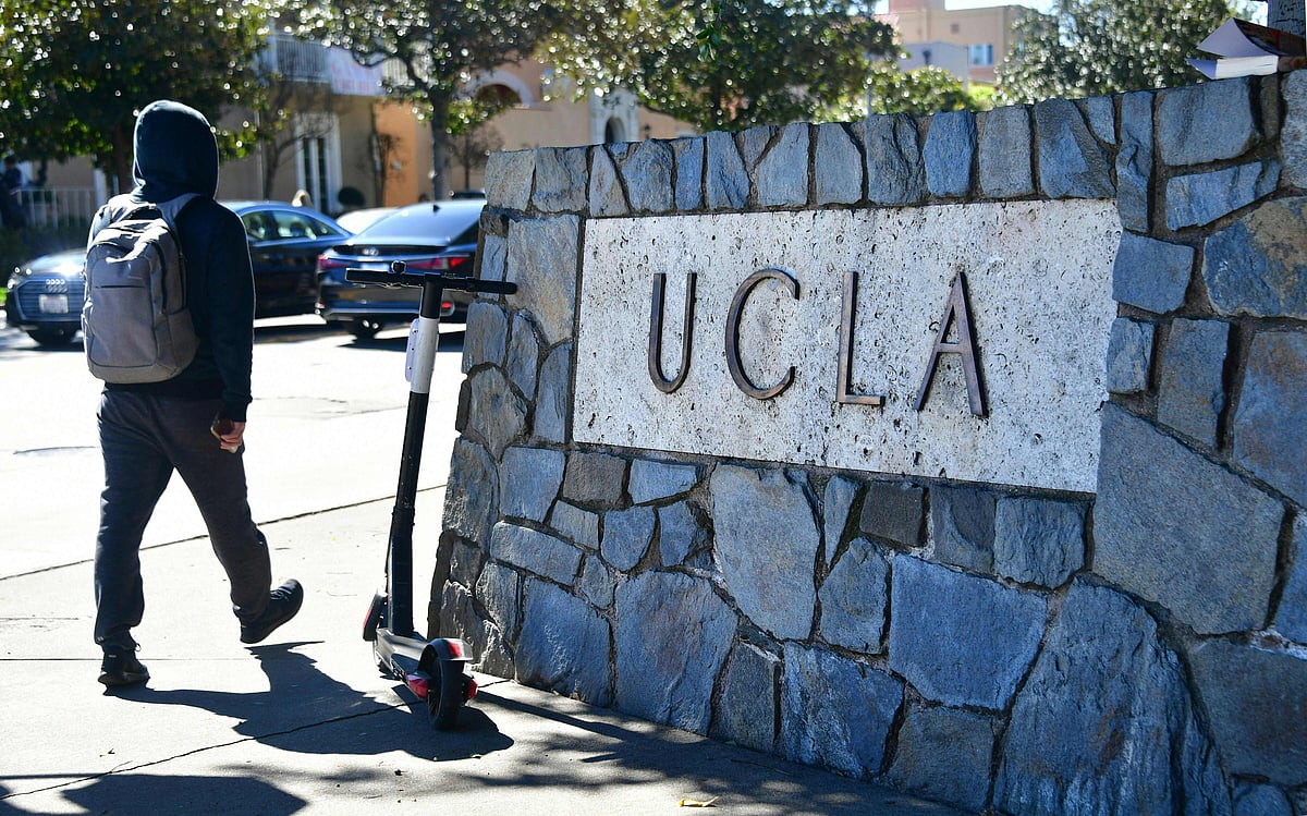 A man with a backpack walks past a sign at the University of California Los Angeles (UCLA) in Los Angeles, California on 13 March, 2019. President Donald Trump demanded a massive USD 1 billion fine from the prestigious University of California system on 8 August as the administration pushed its claims of antisemitism in UCLA's response to 2024 student protests related to Gaza.