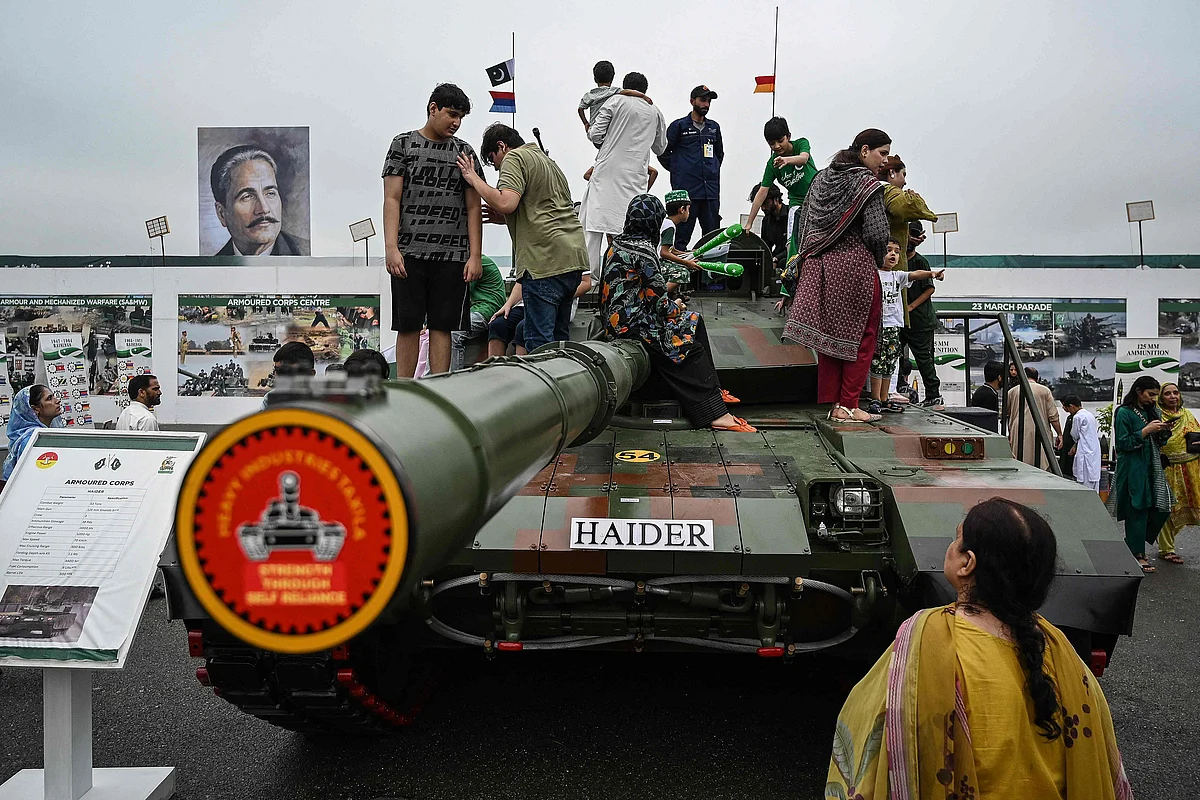 People climb over a military tank at a defence exhibition during Independence Day celebrations in Islamabad on 14 August 2025.
