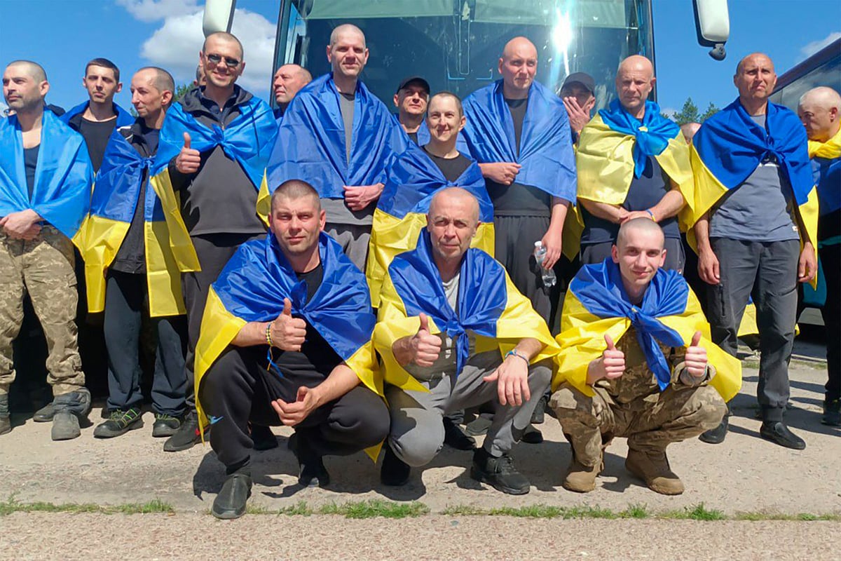 In this handout photograph taken and released by the Coordination Headquarters for the Treatment of Prisoners of War on 14 August, 2025, Ukrainian prisoners of war (POWs), wrapped with Ukrainian national flags, pose for a photo following an exchange at an undisclosed location, amid the Russian invasion in Ukraine.