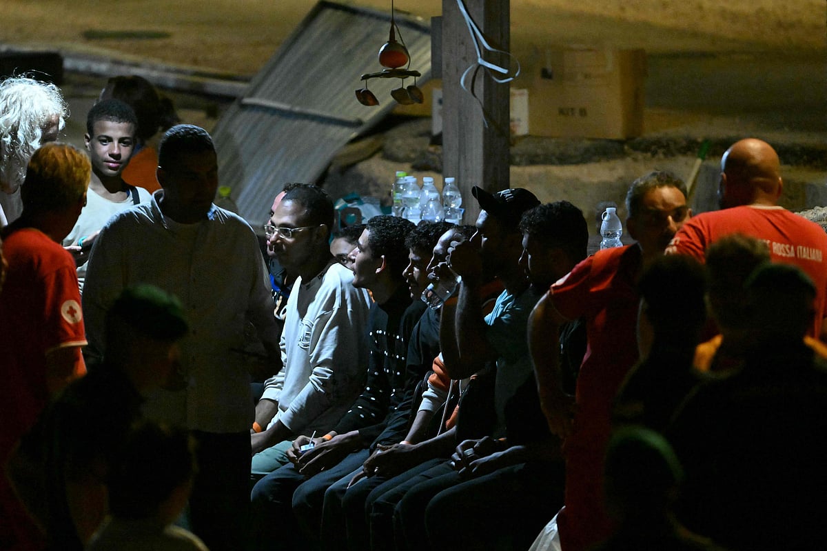A migrant drinks water as he and others wait after disembarking on Lampedusa following their rescue from boats that sank in the Mediterranean Sea off the Italian island of Lampedusa on 14 August 2025.