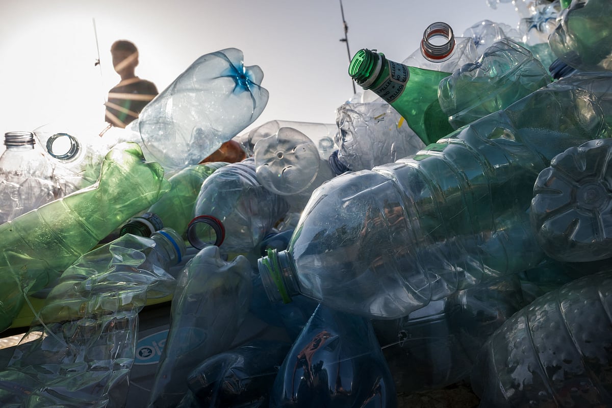 A boy is silhouetted walking past an artwork by Canadian artist, activist, and photographer Benjamin Von Wong entitled "The Thinker's Burden" a 6-meter-tall sculptural remix of Rodin's iconic Thinker, which is being created for the Plastics Treaty Negotiations is seen in front of the United Nations Offices in Geneva on 15 August, 2025.