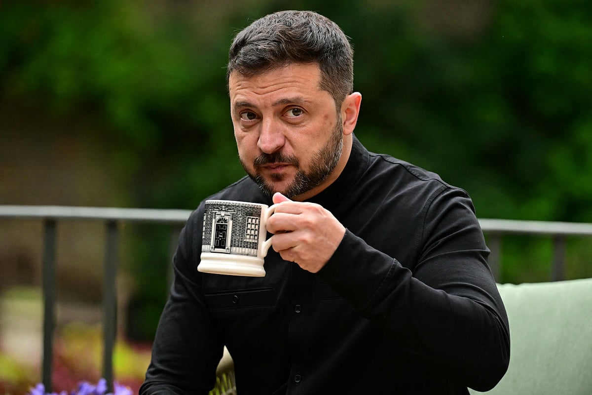 Ukraine's President Volodymyr Zelensky drinks from a Downing Street -themed mug as he sits with Britain's Prime Minister Keir Starmer (unseen) in the garden of 10 Downing Street in central London, on 14 August 2025.