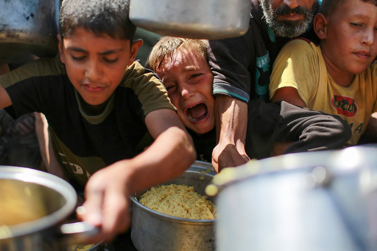 People try to get rice from a charity kitchen providing food for free in the west of Gaza City, on 28 August, 2025.