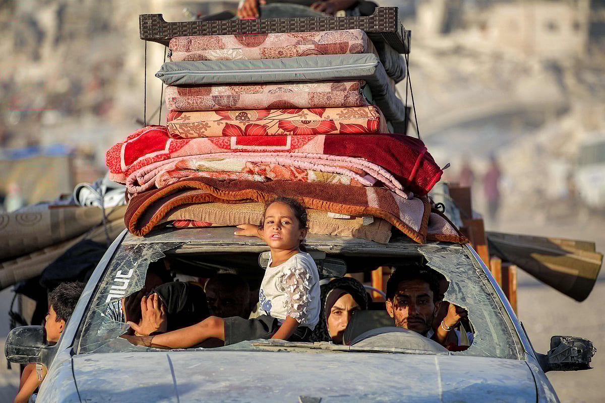 A girl rides through the broken windshield at the front of a vehicle transporting people and their belongings while evacuating southbound from Gaza City on 2 September, 2025