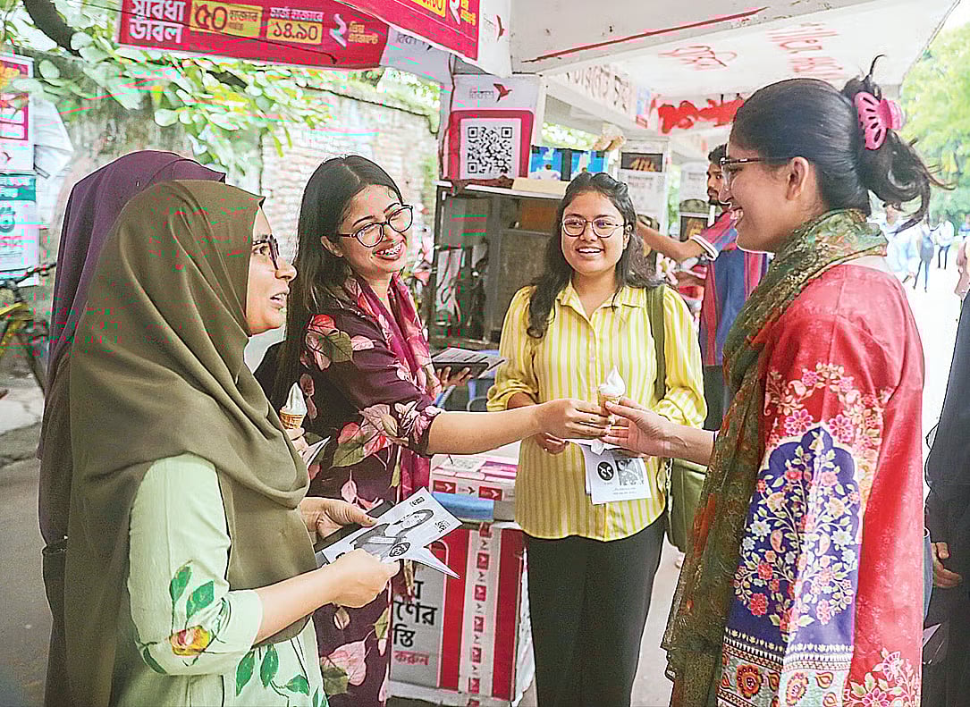 A student offers an ice cream to Umama Fatema (R), Vice President candidate from the Independent Student Unity panel, during the DUCSU election campaign at the Arts Building area of Dhaka University on 4 September 2025.