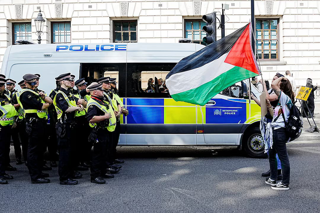 Demonstrators hold a Palestinian flag in front of police officers, on the day of the "Lift The Ban" rally organised by Defend Our Juries, challenging the British government's proscription of "Palestine Action" under anti-terrorism laws, in Parliament Square, in London, Britain, 6 September, 2025.