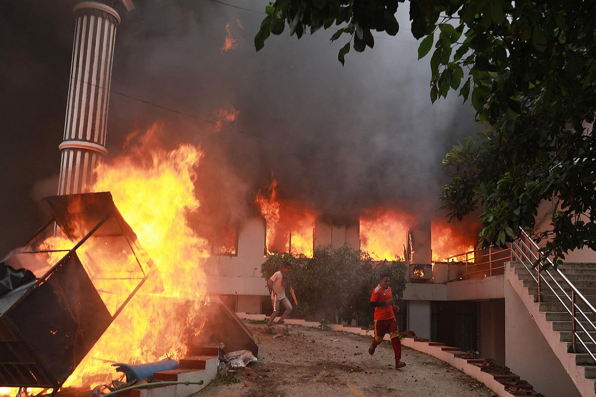 Demonstrators run past flames outside the burning Nepali Congress Party office during a protest to condemn the police's deadly crackdown on demonstrators in Kathmandu on 9 September, 2025