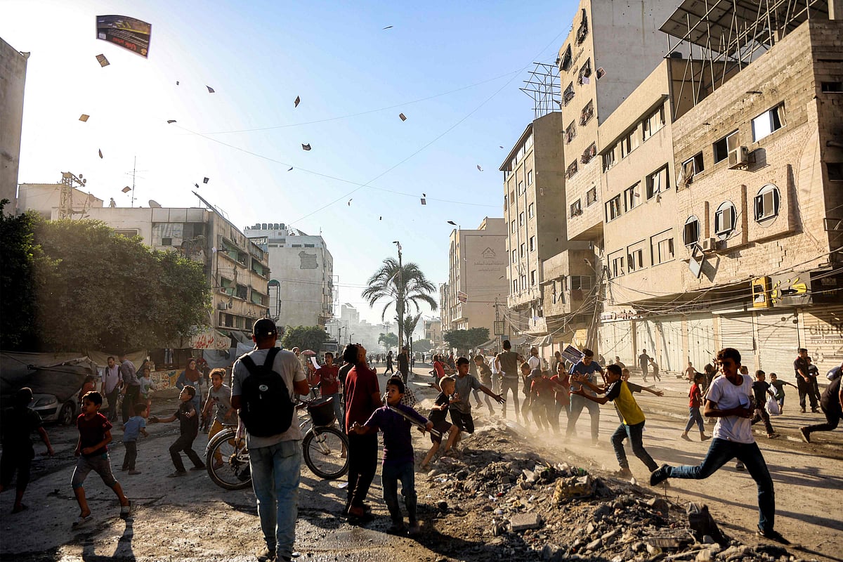 People watch as leaflets dropped by the Israeli military, urging evacuation south to al-Mawasi, land in Gaza City on 9 September, 2025.