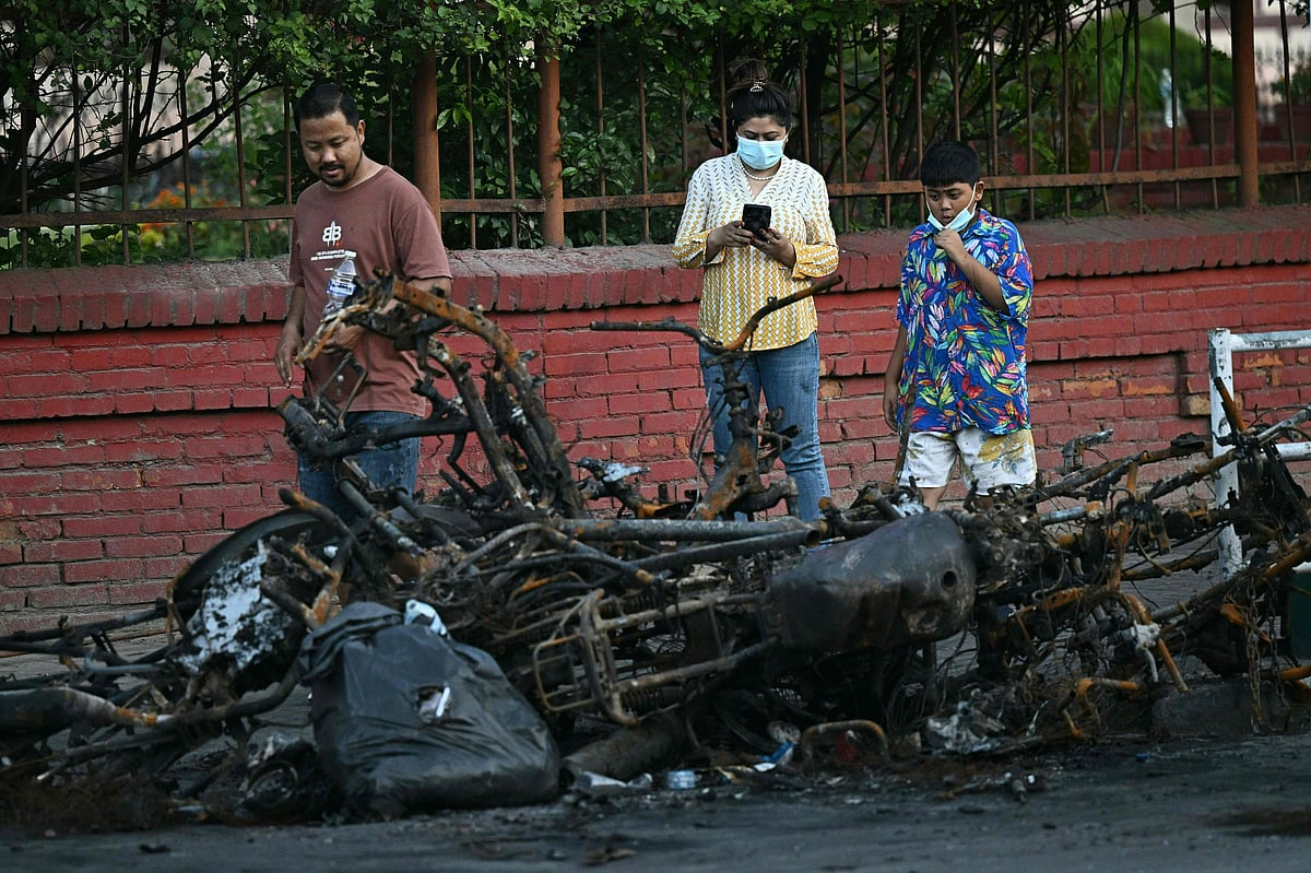 Locals walk past calcined cars near the Supreme Court during a curfew imposed to restore law and order in Kathmandu on 11 September, 2025.