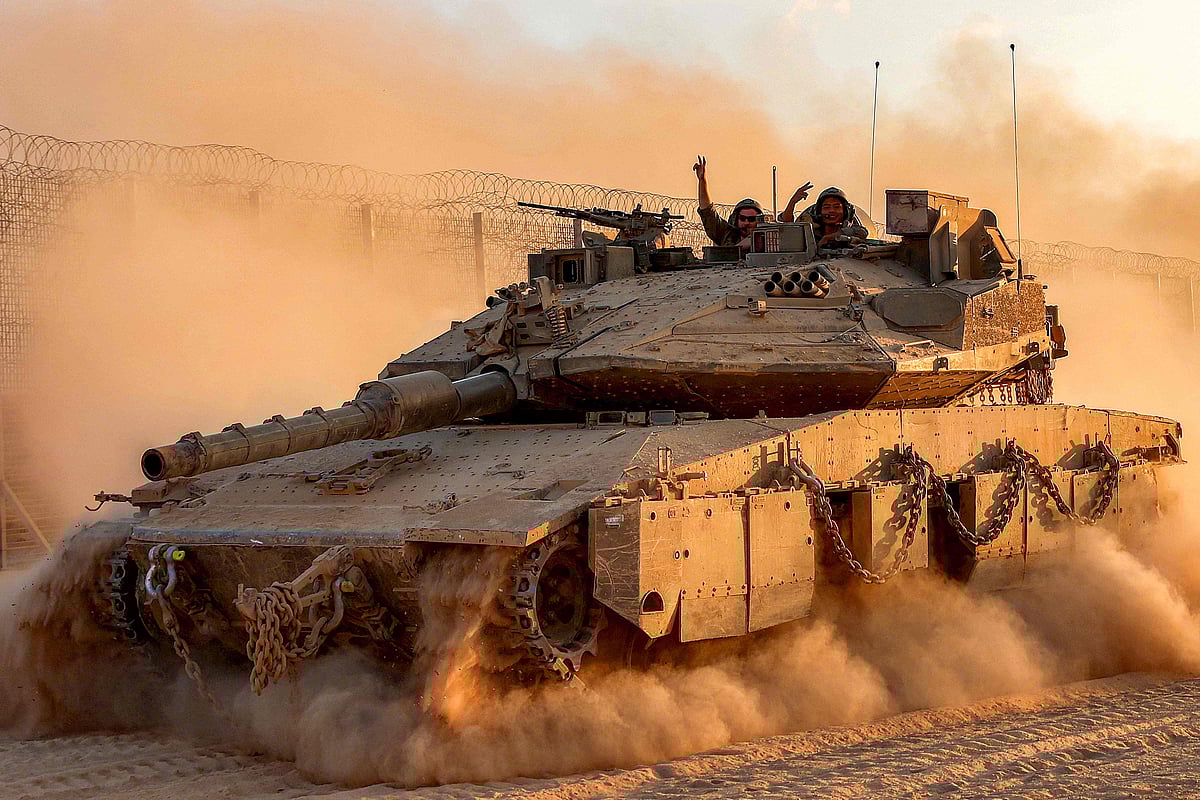 Israeli army soldiers gesture from the turret of a Merkava main battle tank moving at a position along the border fence with the Gaza Strip in southern Israel on 12 September, 2025.