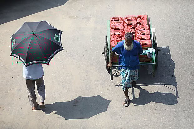 Carrying water in a cycle van in the scorching sun. Another man walks with an umbrella at Humayun Rashid Chattar in Sylhet