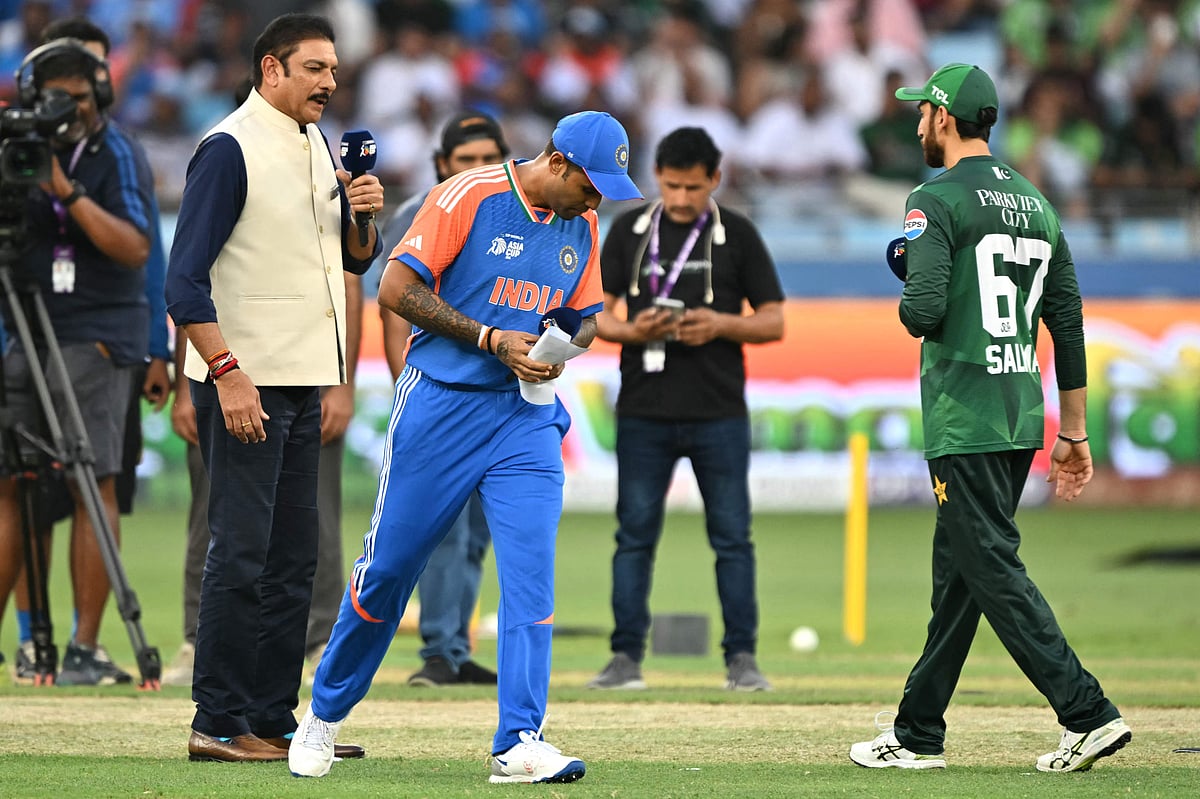 India's captain Suryakumar Yadav (C) walks after the toss as his Pakistan's counterpart Salman Agha (R) watches before the start of the Asia Cup 2025 Super Four Twenty20 international cricket match between India and Pakistan at the Dubai International Stadium in Dubai on 21 September, 2025
