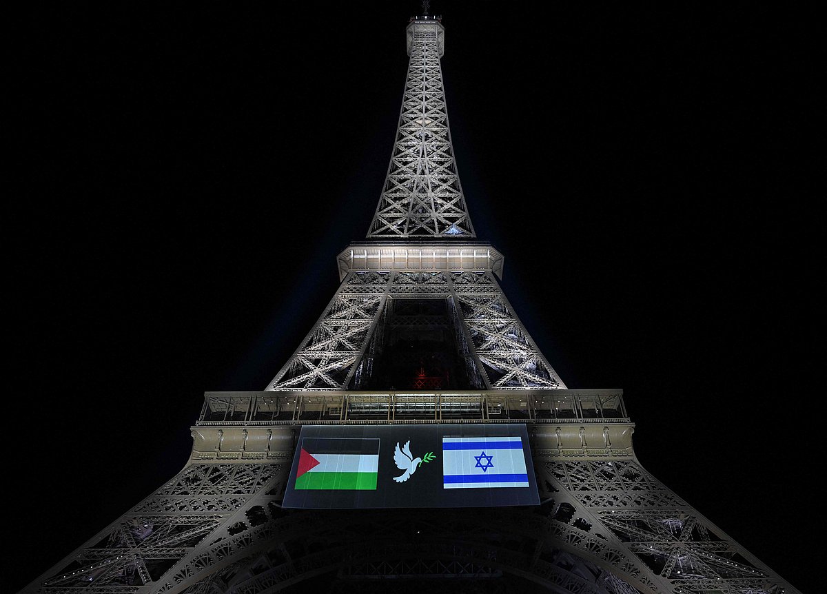 This photograph shows images of Palestinian (L) and Israeli (R) flags and a dove with an olive olive branch, projected onto the Eiffel Tower on the eve of France's planned recognition of the State of Palestine, in Paris, on 21 September, 2025.