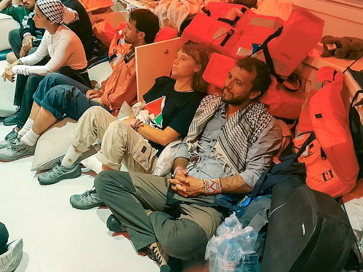 This handout picture released by the Israeli Foreign Ministry shows Swedish climate activist Greta Thunberg (C) and Brazilian activist Thiago Avila (R), along with other activists, after the Israeli navy intercepted the Global Sumud Flotilla carrying humanitarian aid to Gaza on 1 October, 2025, as stated by the ministry.