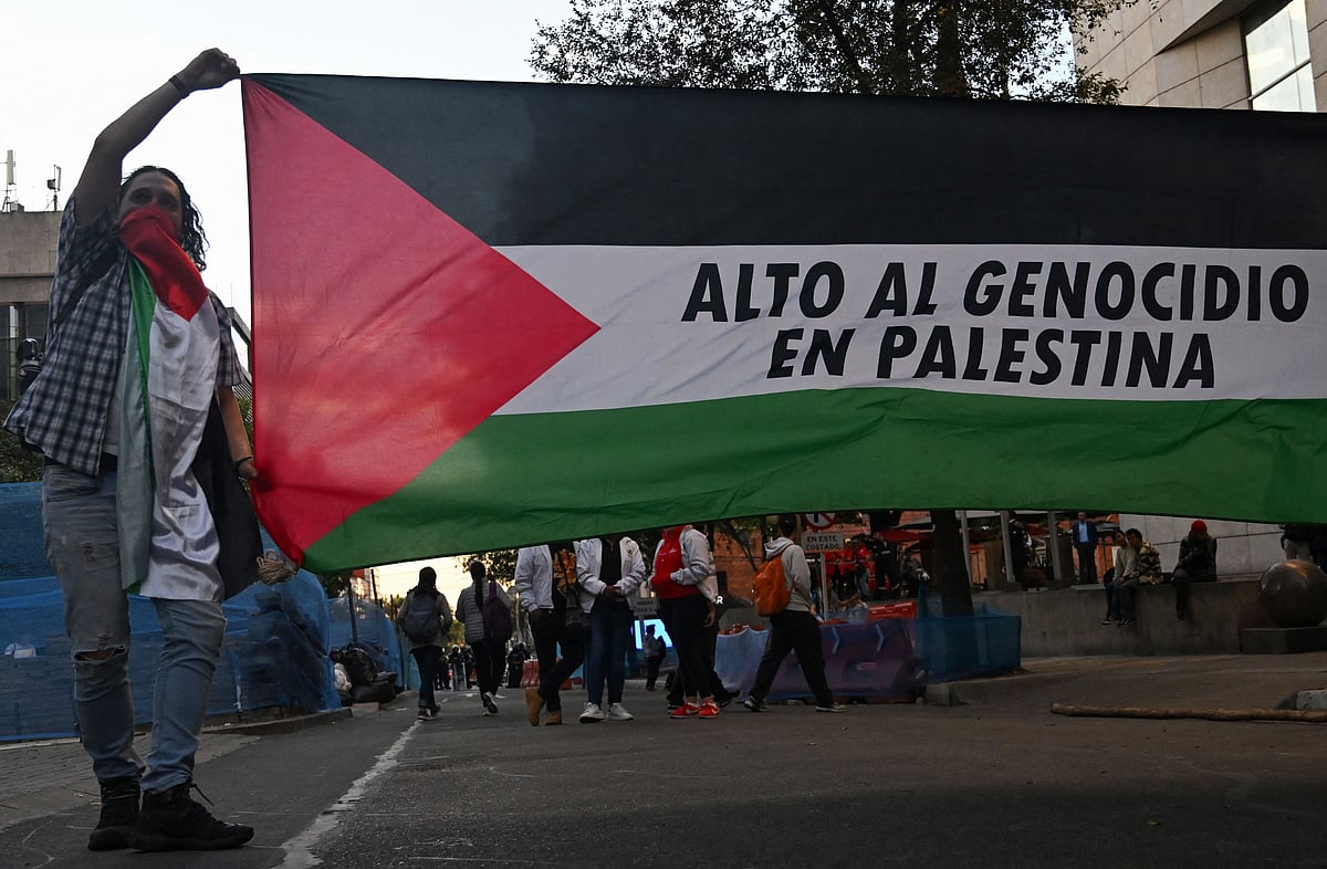 A demonstrator holds a giant Palestinian flag reading ‘Stop genocide in Palestine’ during a protest in solidarity with Palestinians and to condemn the interception of the Global Sumud Flotilla by the Israeli army in Bogota on 2 October, 2025