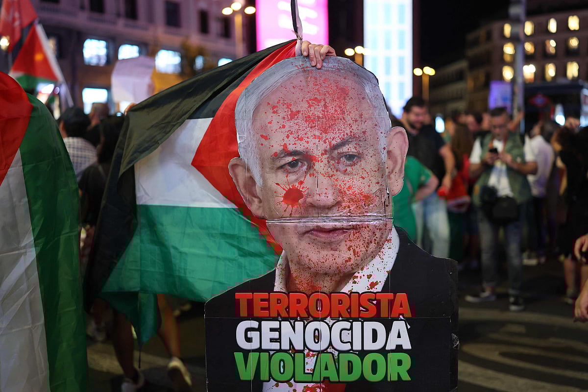 A protester holds a defaced poster depicting Israeli Prime Minister Benjamin Netanyahu with the words "Terrorist, Genocidal, Rapist" during a demonstration in solidarity with the Palestinians in the Gaza strip, in Madrid on October 4, 2025