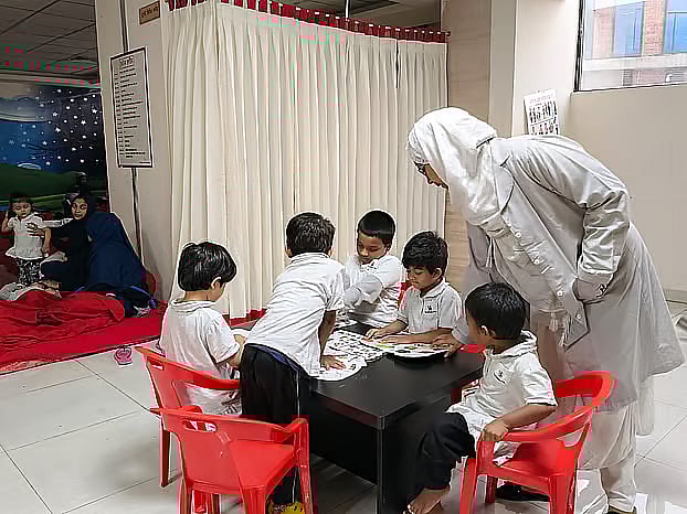 A few children sit around a table— a glimpse from 18 December at the daycare centre located in the Water Development Board building in Dhaka.