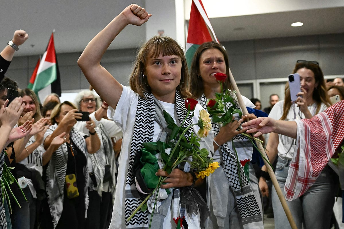 Swedish climate campaigner Greta Thunberg raises her fist, upon arrival alongside activists who were sailing aboard vessels from the Gaza-bound aid flotilla before being stopped and detained by Israeli forces, greeted by a crowd of supporters, at the arrivals area of Athens International Airport on 6 October 2025