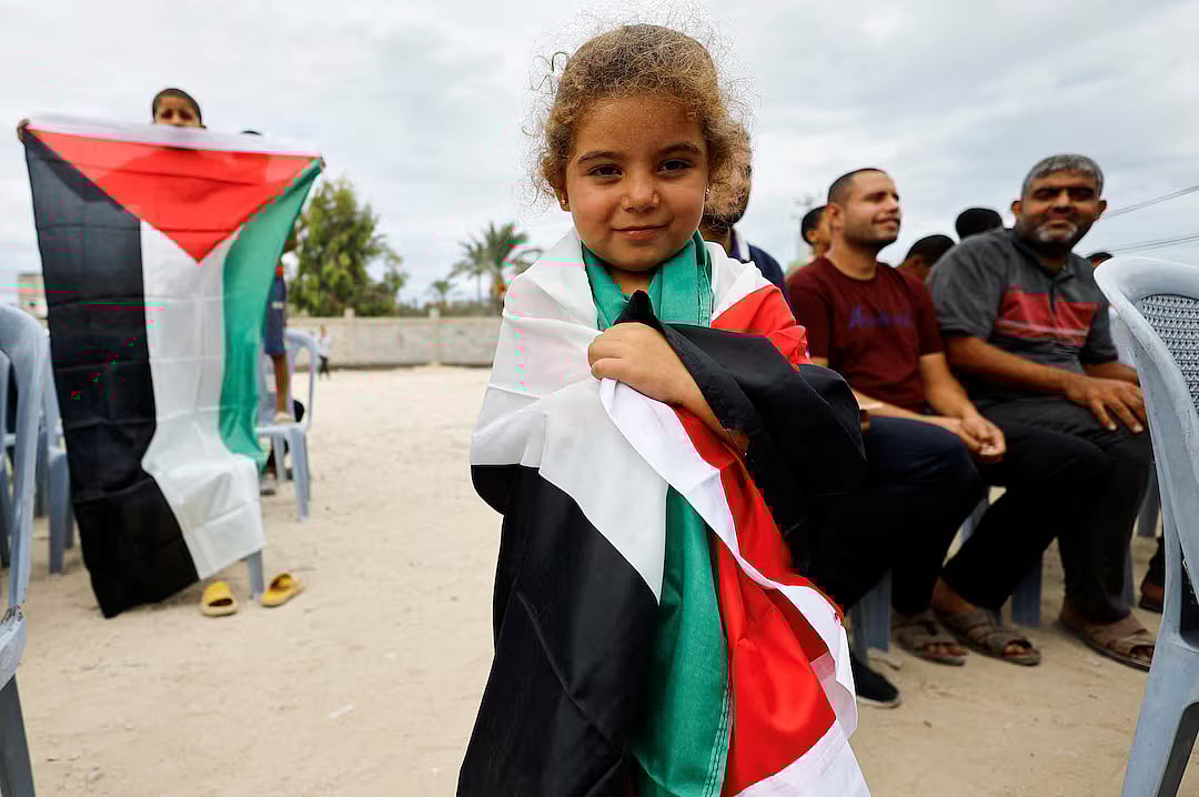 A girl holds a Palestinian flag, after Israel and Hamas agreed on the first phase of a Gaza ceasefire, in the central Gaza Strip, 9 October.