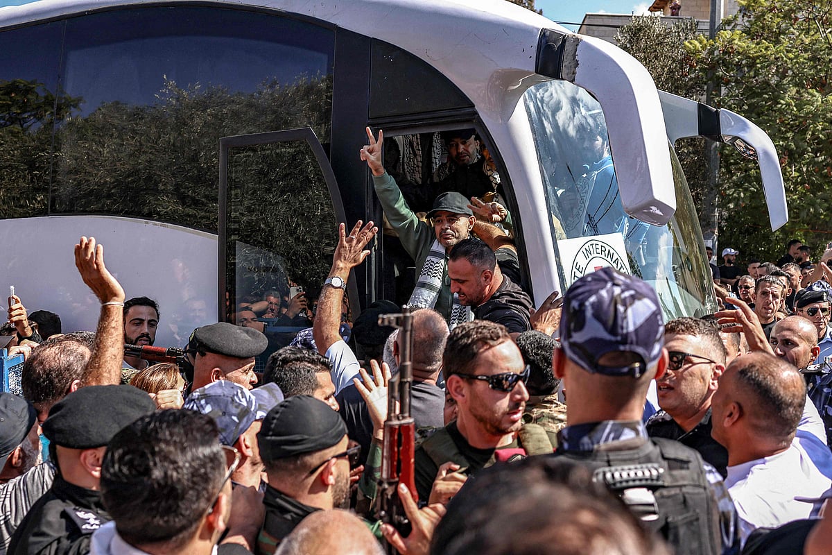 One of the Palestinian prisoners, who was released in a prisoner-hostage swap and ceasefire deal between Israel and Hamas, gestures as he and others disembark from their bus upon arrival at Ramallah Cultural Centre in Ramallah in the occupied West Bank, on 13 October, 2025