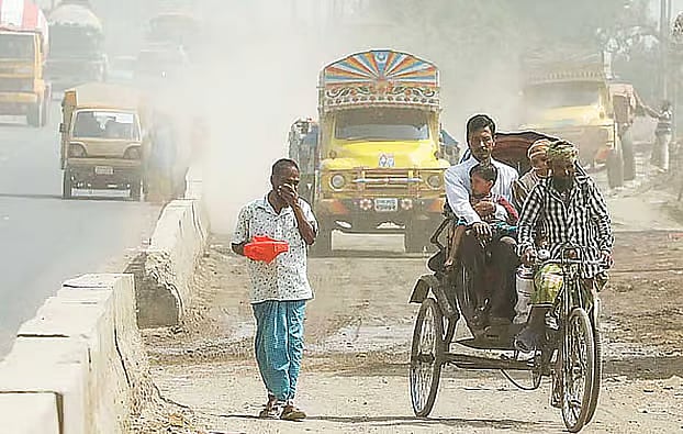 A man covers his nose as he walks amid polluted air in Dhaka