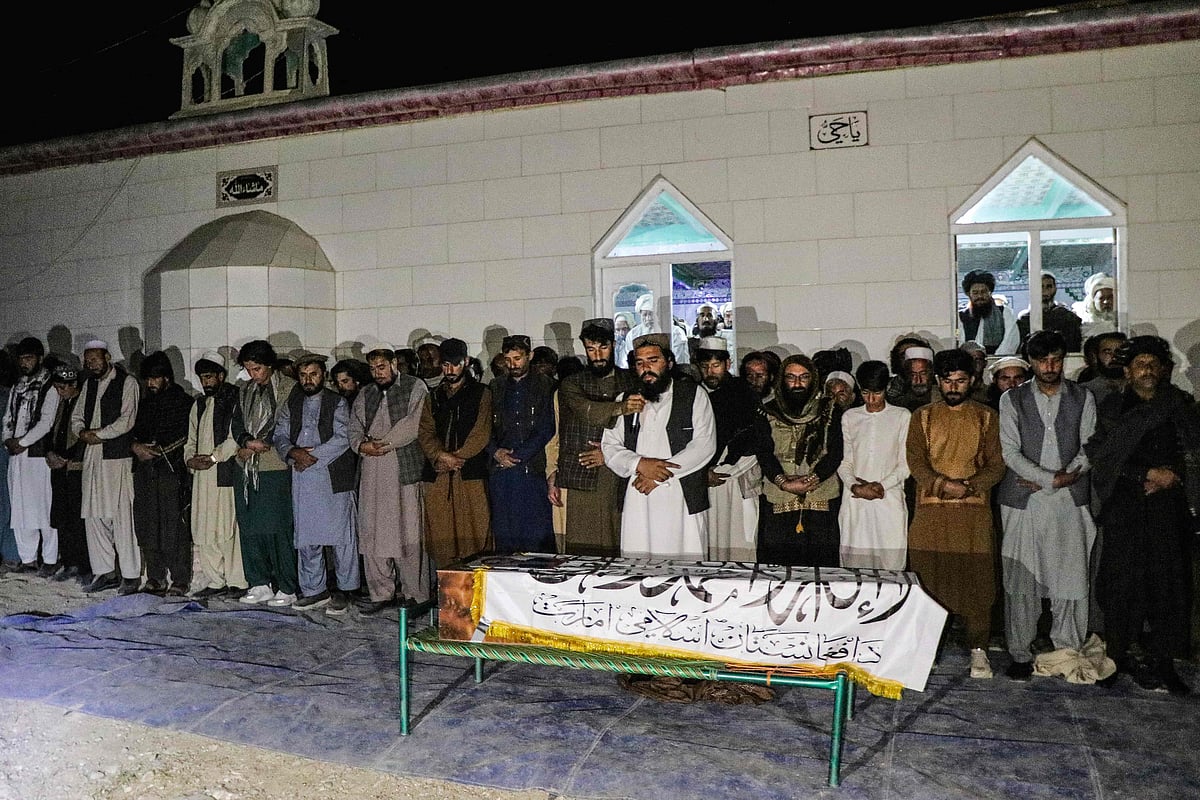 Afghan mourners and relatives gather around the Taliban flag-shrouded coffin of late Abdul Ghafoor Abid, a local reporter for the broadcasting organization National Radio Television of Afghanistan (RTA), during his funeral and burial ceremony at a village in the Ahmad Aba district of Paktia province on 15 October, 2025