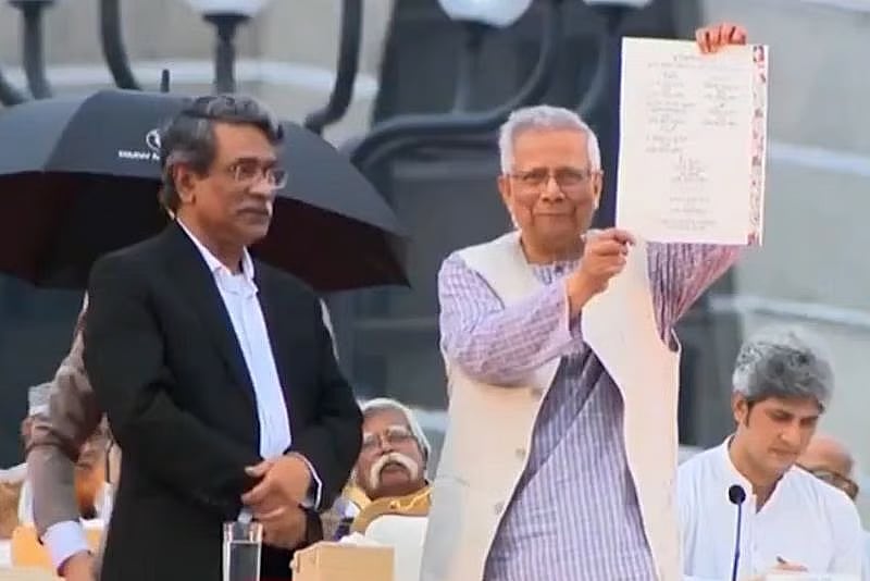 Interim government chief adviser professor Muhammad Yunus shows the signed July National Charter as National Consensus Commission vice-chairman Ali Riaz watches at South Plaza of National Parliament in Dhaka on 17 October 2025