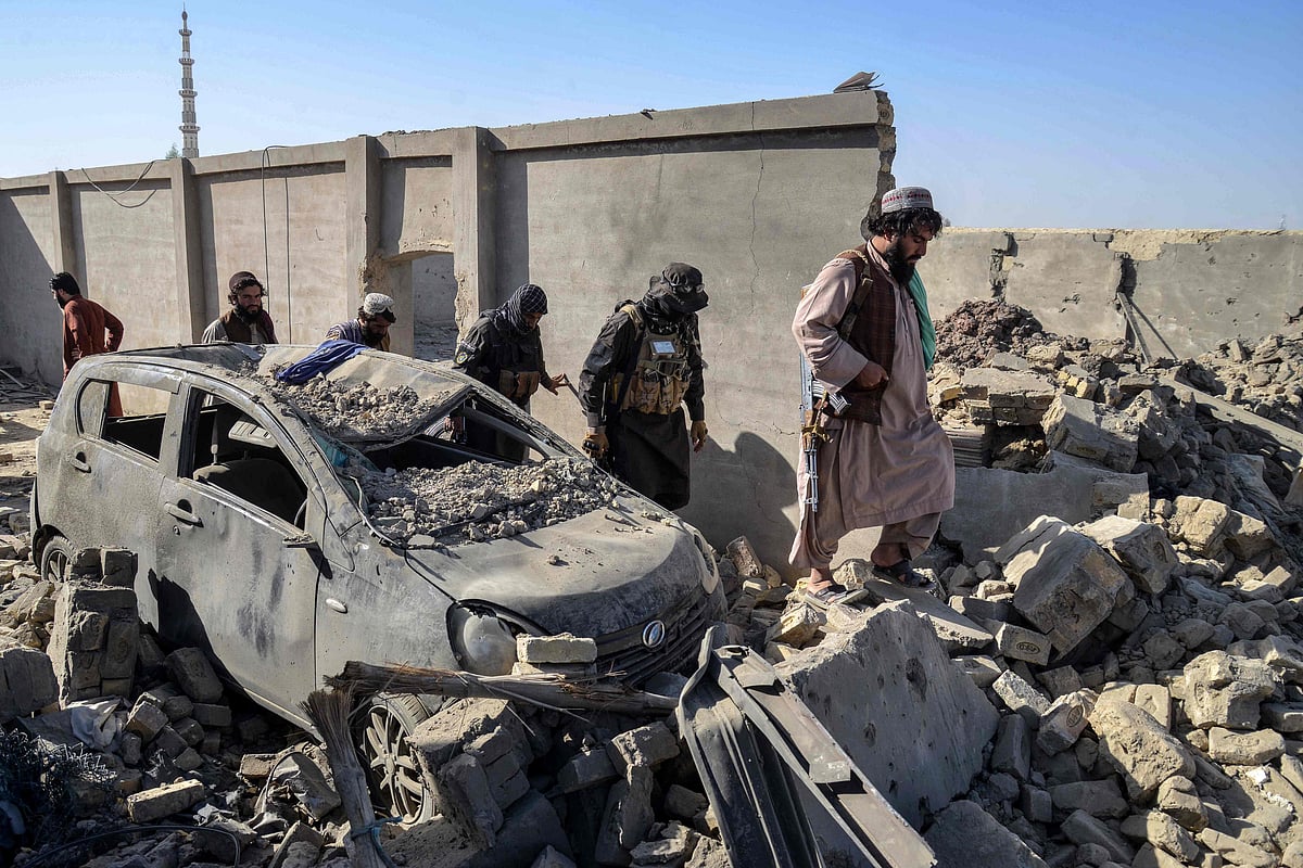 aliban security personnel walk past a damaged car in the Spin Boldak district of Kandahar province on 16 October, 2025, a day after the cross-border clashes between Afghanistan and Pakistan.