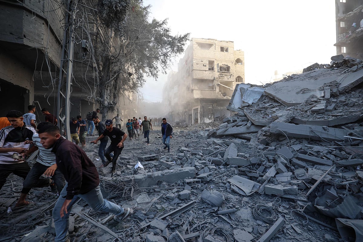 People run for cover following an Israeli strike that targeted a building in the Bureij camp for Palestinian refugees in the central Gaza Strip on 19 October, 2025.
