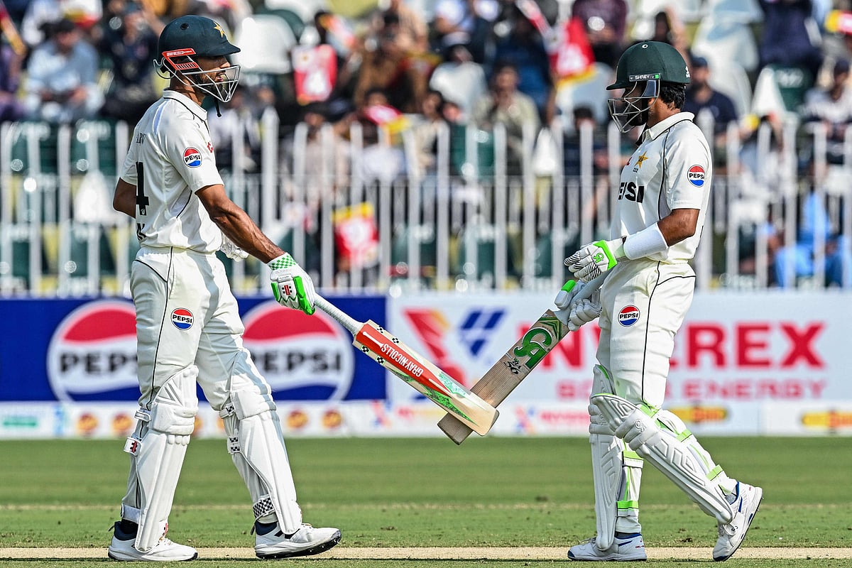 Pakistan's captain Shan Masood (L) and his teammate Babar Azam bump their bats during the first day of the second Test cricket match between Pakistan and South Africa at the Rawalpindi Cricket Stadium in Rawalpindi on 20 October, 2025