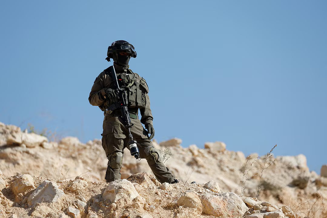 A member of the Israeli force stands guard as the Israeli forces block the access of Palestinians and foreign activists to olive trees during the olive harvest, near Hebron, in the Israeli-occupied West Bank, 23 October, 2025.