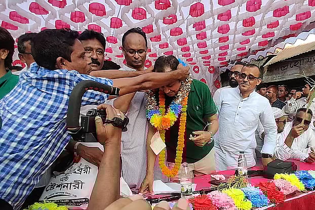 Nur Kashem (check shirt) tying a check worth Tk 10 million to BNP leader Kamruzzaman on the rally stage in Sunamganj on 25 October 2025
