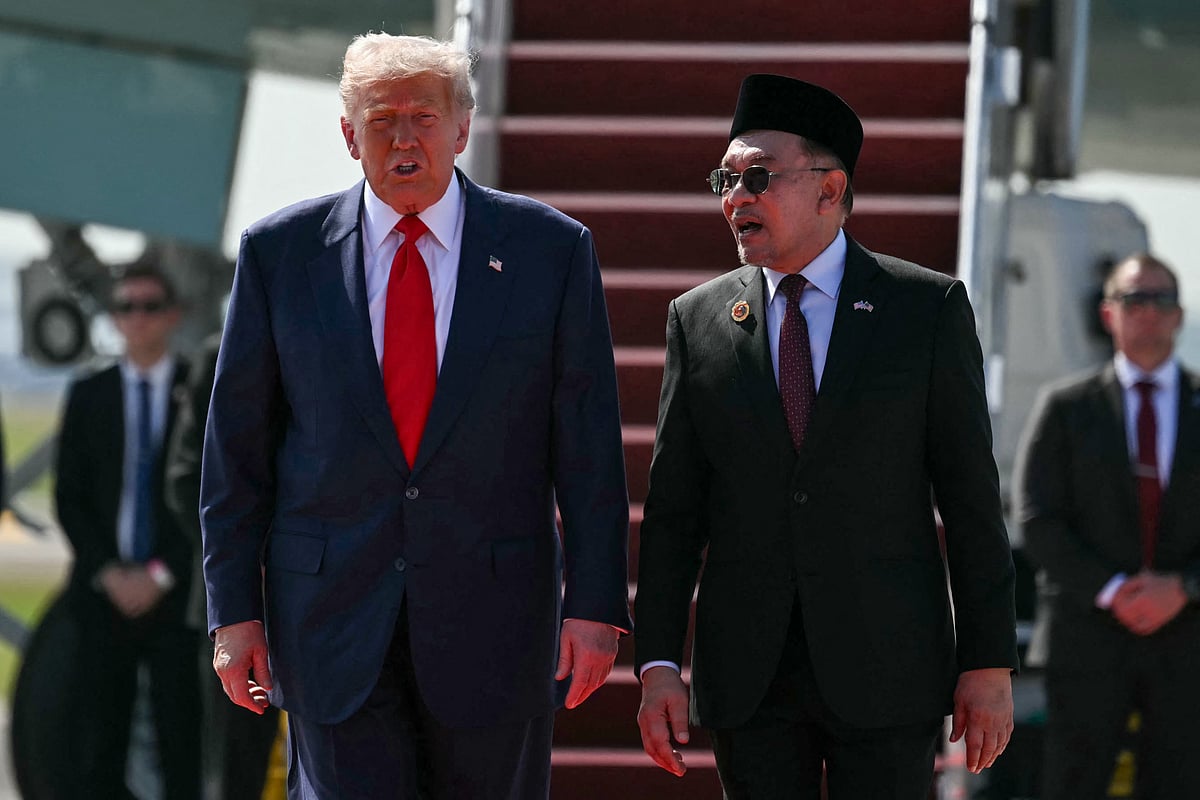 US President Donald Trump (L) speaks with Malaysia's Prime Minister Anwar Ibrahim (R) as he walks from Air Force One upon arrival at Kuala Lumpur International Airport in Kuala Lumpur on 26 October, 2025.