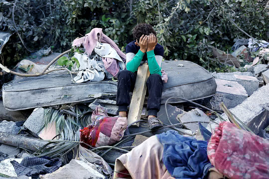 A Palestinian boy reacts as he sits at the site of an overnight Israeli strike on a house, in Nuseirat, central Gaza Strip, 29 October, 2025.