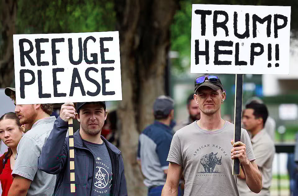 Demonstrators hold placards in support of US President Donald Trump's stance against what he calls racist laws, land expropriation, and farm attacks, outside the American Embassy in Pretoria, South Africa, on 15 February, 2025.