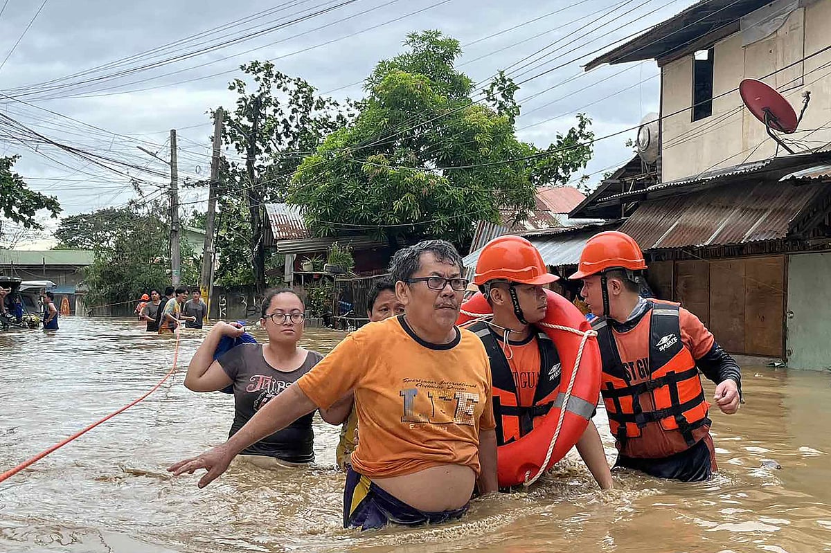 This handout photo taken and released on November 4, 2025 by the Philippine Coast Guard (PCG) shows coast guard personnel evacuating people from their flooded homes following heavy rains brought about by Typhoon Kalmaegi in Cebu province, central Philippines.
