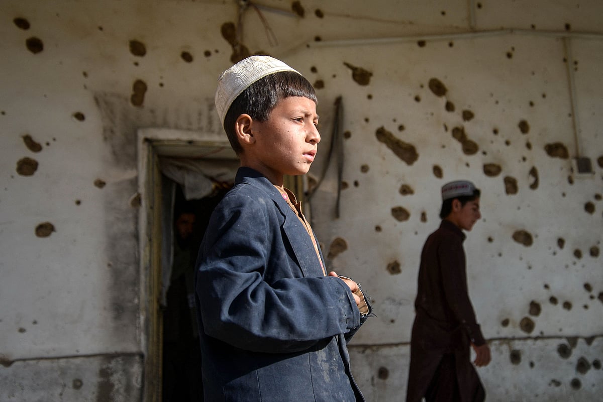 Afghan boys walk past a damaged house, following cross-border fire from Pakistan's artillery shelling, at a village in the Spin Boldak district of Kandahar on 7 November, 2025.