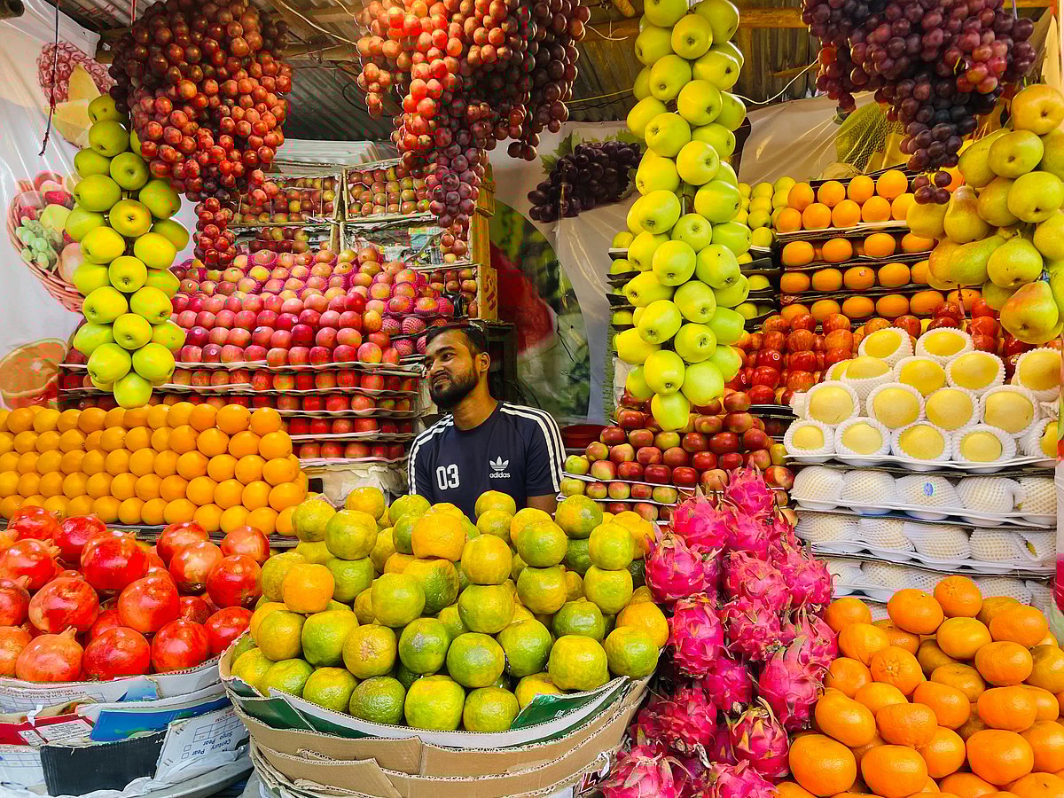 A fruit vendor arranging a variety of local and imported fruits for sale. Kandirpar, Cumilla, 11 November.
