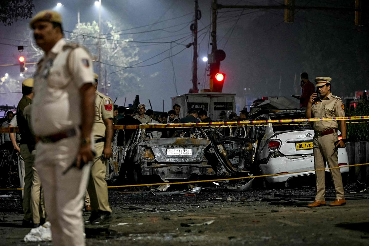 Police personnel inspect charred vehicles as they codorn off the blast site after an explosion near the Red Fort in the old quarters of Delhi on 10 November, 2025.