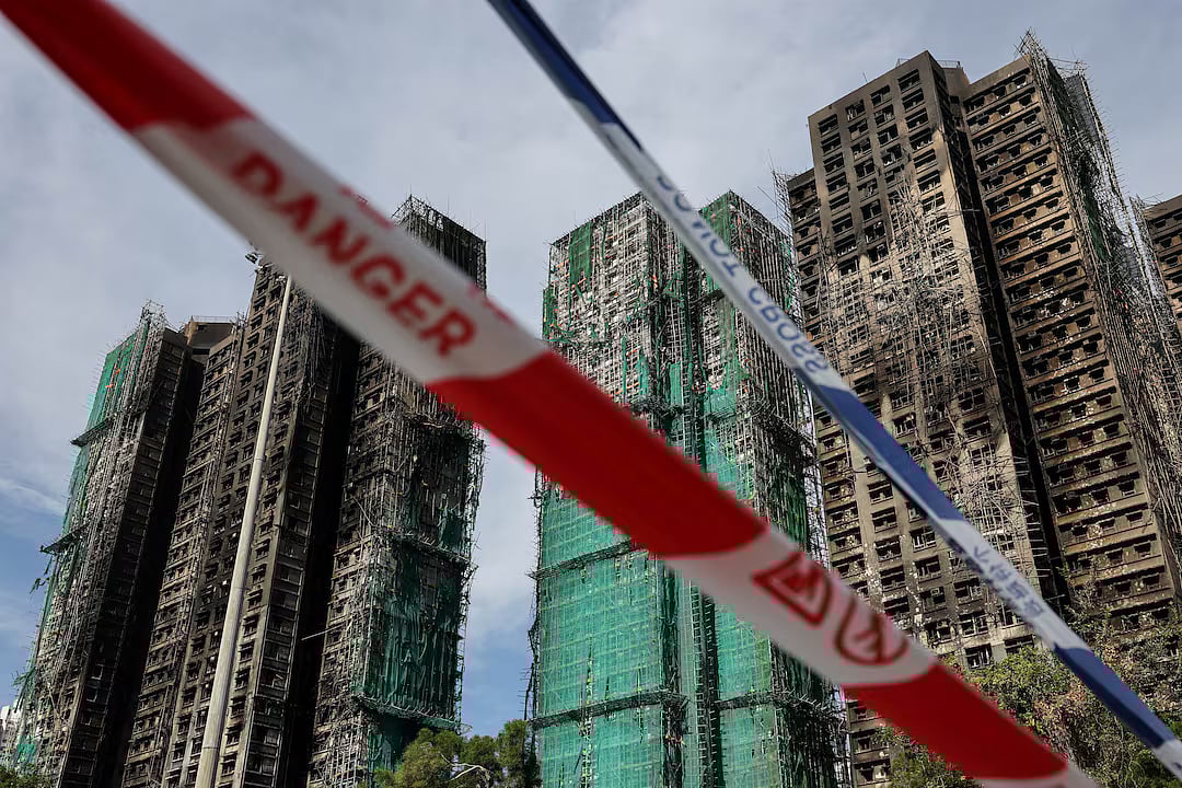 Police cordons are placed at the scene of the Wang Fuk Court housing estate fire as mourners pay tribute to the victims, in Tai Po, Hong Kong, China, 28 November, 2025.