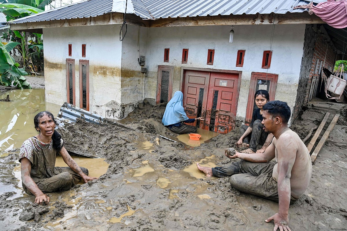 Residents clear deep mud from the entrance of an inundated home following flash floods in Meureudu, Pidie Jaya district in Indonesia's Aceh province on 28 November, 2025