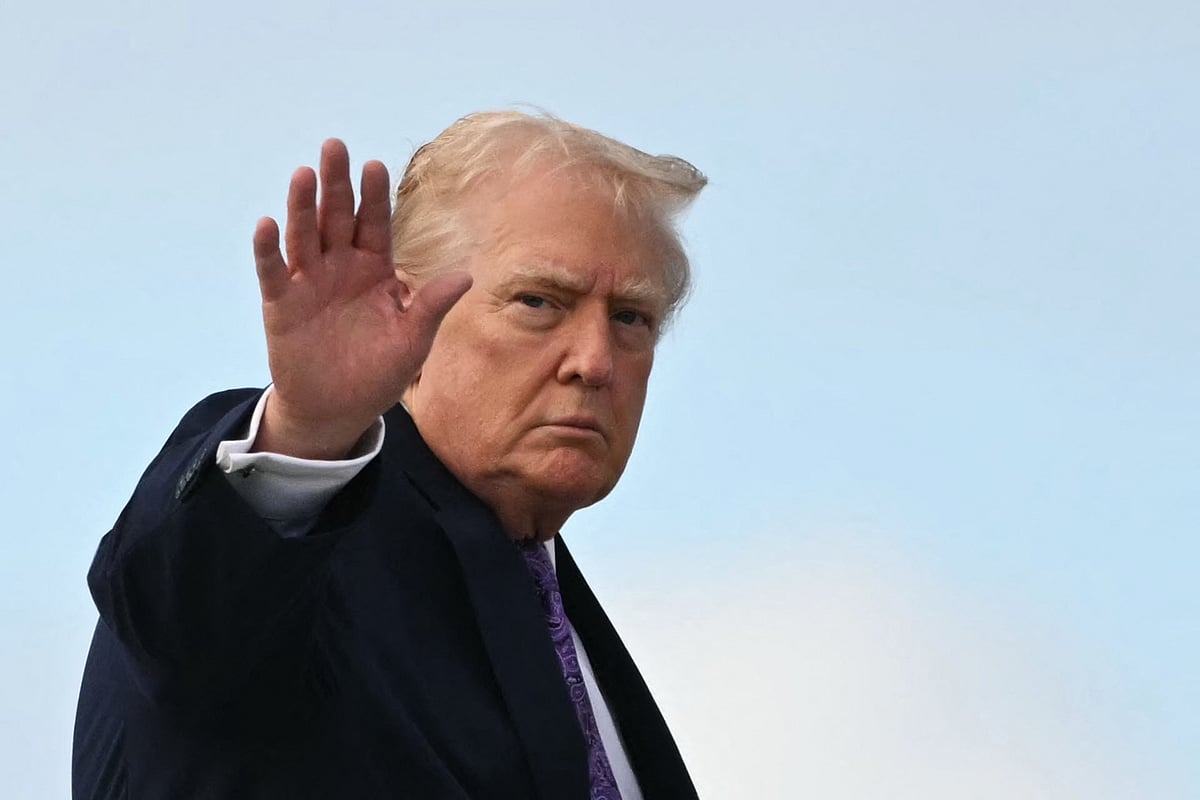 US President Donald Trump waves while boarding Air Force One at Palm Beach International Airport on 30 November, 2025, on their way back to Washington, DC.